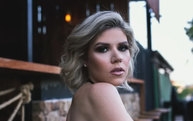 Elegant portrait of a blonde woman with short hair, captured outdoors in natural lighting.