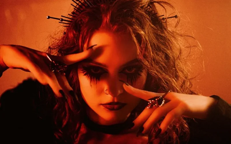 Expressive portrait of a woman with gothic makeup and accessories.