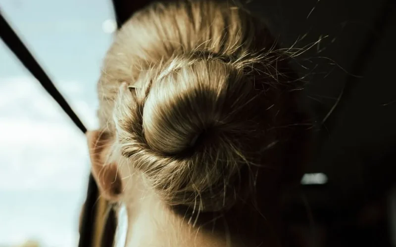 Close-up of a blonde hair bun illuminated by sunlight, showcasing elegant fashion.