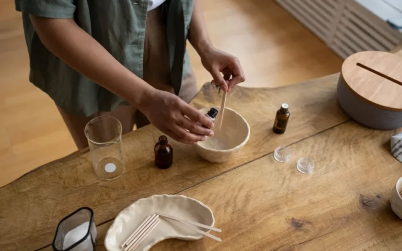 Close-up of hands making homemade lip balm in a cozy indoor setting.