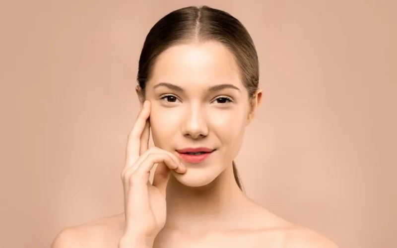 A close-up portrait of a young woman with flawless, radiant skin and a gentle smile, exuding natural beauty.