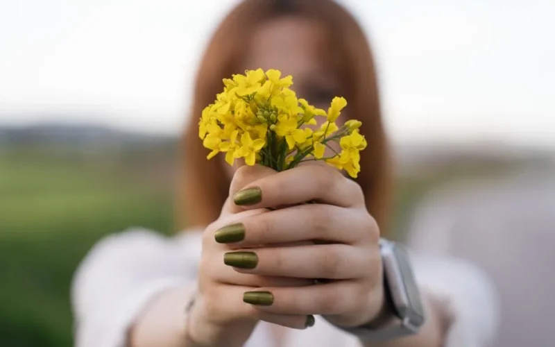 Close-up of a woman holding yellow flowers with green nails in Merzifon, Türkiye.
