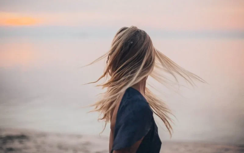 Blonde woman enjoying a serene sunset by the beach, capturing the essence of tranquility.
