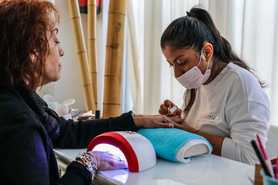 Nail technician providing a manicure service in a salon setting.