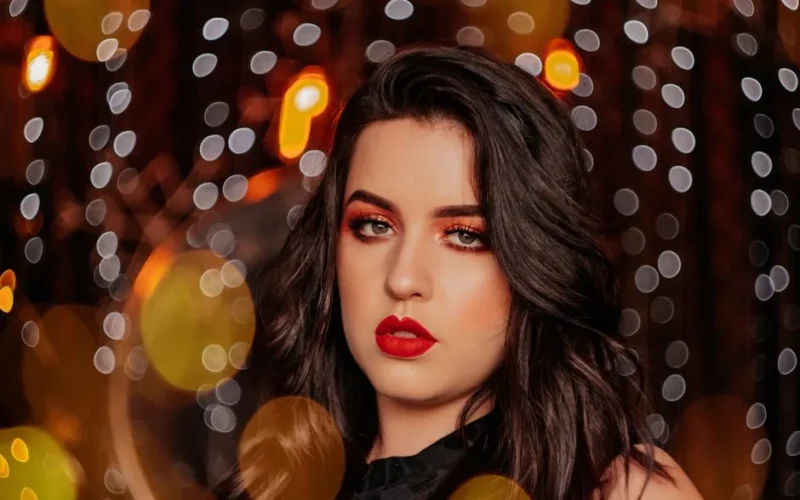 Elegant close-up of a woman with bold makeup in a bokeh lights setting.