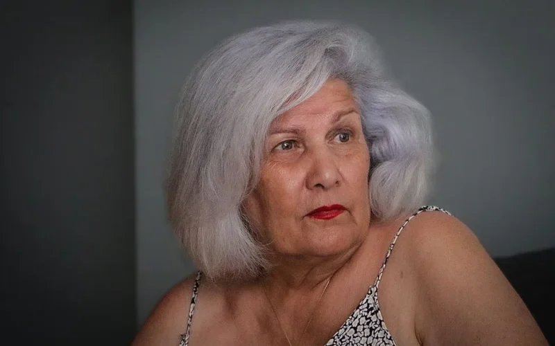 Portrait of an elderly woman with silver hair, looking thoughtfully to the side.