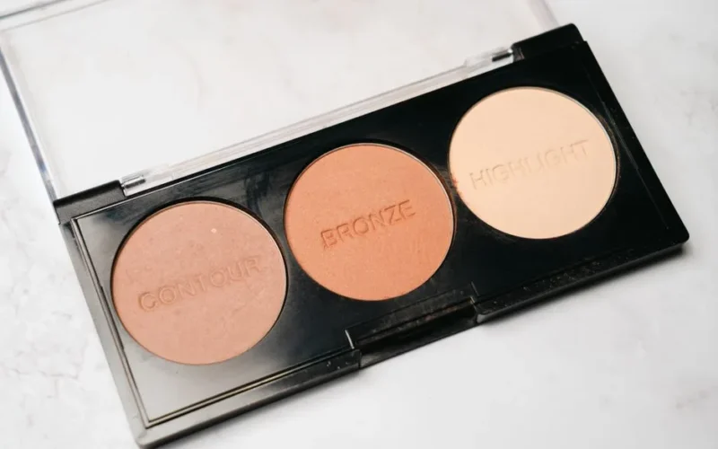 Close-up of a makeup palette featuring contour, bronze, and highlight powders.