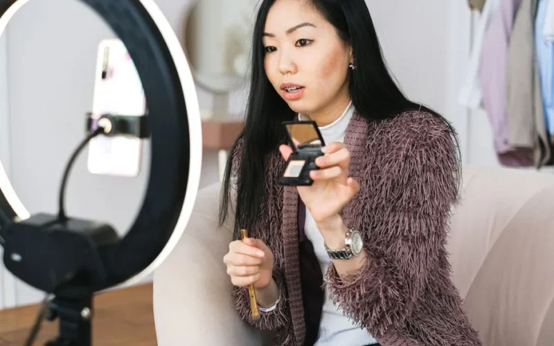Young woman recording a makeup tutorial with a ring light for her vlog.