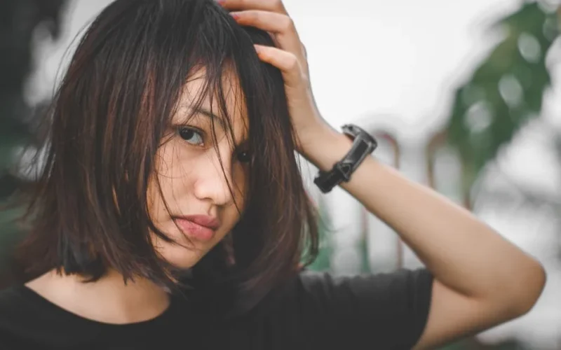 Close-up portrait of a young woman with messy hair, outdoors in Banten, Indonesia.