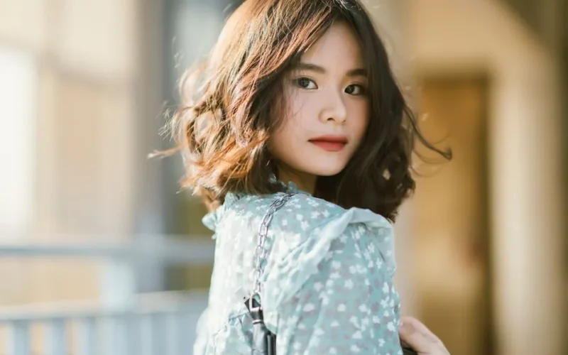 Elegant portrait of an Asian woman wearing a floral dress outdoors.