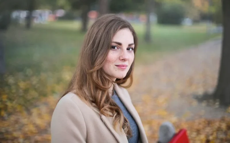 A woman smiles in an autumn setting in Budapest, Hungary.