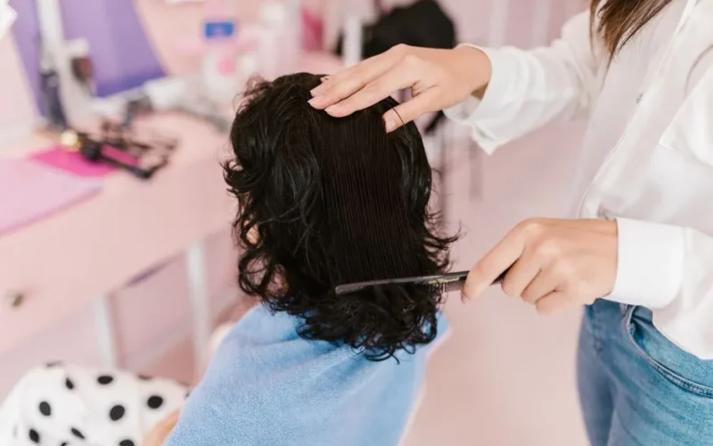 Close-up of a woman receiving hairstyling treatment in a contemporary salon.