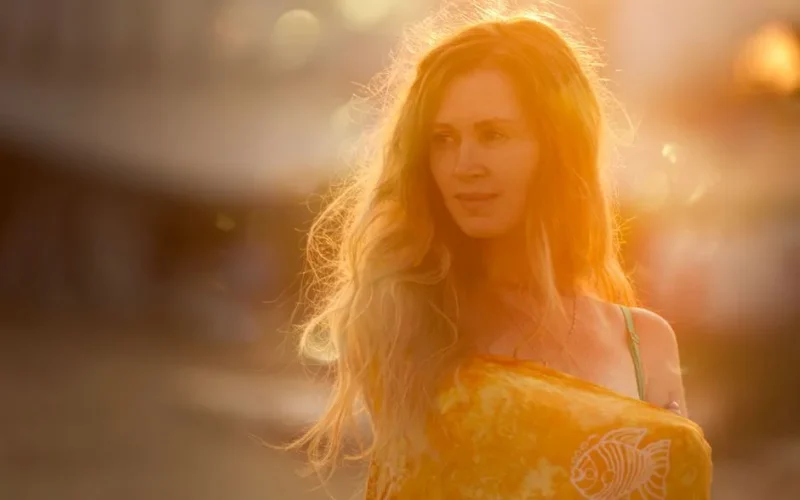 Sunlit portrait of a smiling woman with long hair in a bright, warm setting.