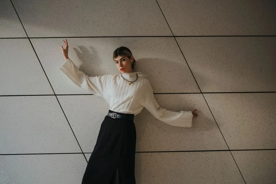 Stylish woman in chic attire posing against a geometric wall in Berlin.
